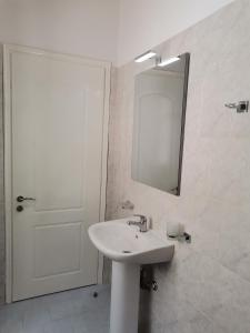 a white bathroom with a sink and a mirror at Spilia Apartments in Stavros +39 photos