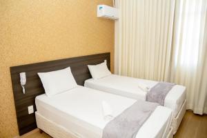 two beds in a hotel room with white sheets at Hotel GMatos Belo Horizonte - Próximo a Rodoviária e Mercados Turísticos in Belo Horizonte