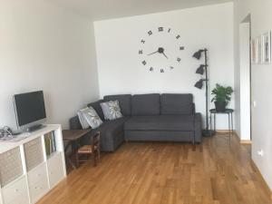 a living room with a couch and a clock on the wall at Strelnieku Apartment in Sigulda