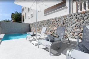 a group of chairs and an umbrella next to a pool at Villa Ona in Port de Soller