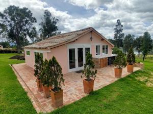 ein kleines rosafarbenes Haus mit Topfbäumen im Hof in der Unterkunft Hacienda El Pinar del Viento in Villa de Leyva