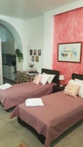 twee bedden in een kamer met rode muren bij Lolos' house in Rhodos-stad