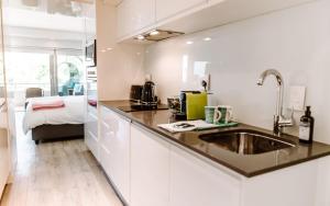 een keuken met een wastafel en een bed in een kamer bij Clifton Studio in Kaapstad