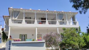 a white house with balconies and flowers on it at Iason studio 2 in Patitiri