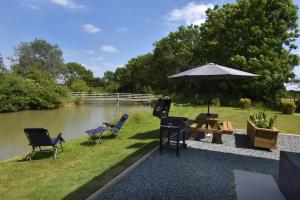 een tafel en stoelen en een parasol naast een rivier bij col's mere in Upton