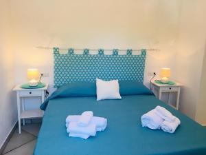 1 dormitorio con 1 cama azul con toallas y 2 mesas en Beach House Ilaria - Turchese Apt, en Olbia