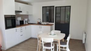 a kitchen with a table and white cabinets and a table and chairs at Appartement indépendant dans maison individuelle in Velleron