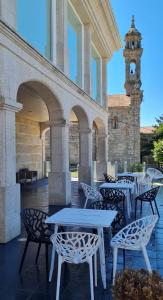 a patio with tables and chairs and a clock tower at Casa Grand Galicia in Junquera de Espadañedo