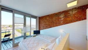 una camera da letto con un muro di mattoni, un letto e una scrivania di Speicher Residenz Barth E5 App 6 a Barth