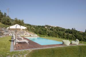 een zwembad met een parasol en een tafel en stoelen bij La Colombiera Relais in Castelnuovo Magra