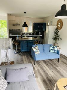 a living room with a blue couch and a kitchen at GÎTE L'ERMITAGE CAHORS in Cahors