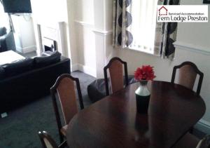 a dining room table with a vase of flowers on it at 4 Bedroom House at Fern Lodge Preston Serviced Accommodation - Free WiFi & Parking in Preston