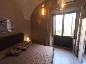 sypialnia z łóżkiem i oknem ze świecą w obiekcie Cortile Pantaleone Holiday Home w Katanii
