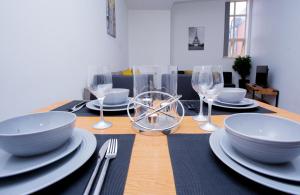 een houten tafel met borden, kommen en wijnglazen bij Spacious Urban City Apartment in Doncaster