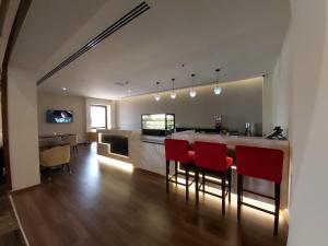 a kitchen with a bar with red chairs in it at Basrah International Airport Hotel in Al Başrah