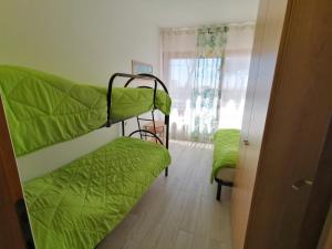 a room with two bunk beds with green sheets at Il MARE alla FINESTRA in Cavallino-Treporti