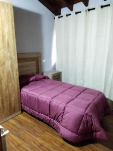 un grande letto viola in una stanza con tende di La Teyera a Infiesto