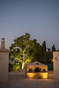 une cheminée en pierre avec des lumières devant un arbre dans l'établissement Droshia Traditional Homes, COCO-MAT Full Experience, à Droushia