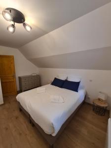 ein Schlafzimmer mit einem großen weißen Bett mit blauen Kissen in der Unterkunft Cottage Naomie in Rue