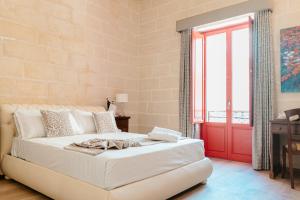 sypialnia z białym łóżkiem i czerwonymi drzwiami w obiekcie Palazzo Violetta Boutique Hotel w mieście Sliema