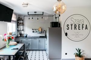 a kitchen with a table and a refrigerator at Szara Strefa - Loft Bieszczady Apartament in Ustrzyki Dolne