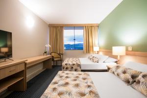 um quarto de hotel com duas camas e uma televisão de ecrã plano em Hotel Golden Park All Inclusive Poços de Caldas em Poços de Caldas