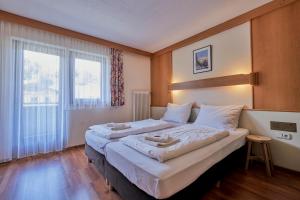 Un dormitorio con dos camas y una gran ventana. en Pension Sonnwend - Inklusiv Gästekarte, en Fieberbrunn