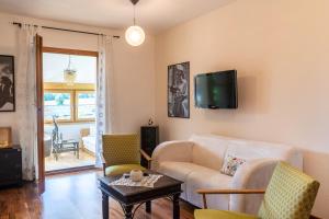 ein Wohnzimmer mit einem Sofa und einem TV an der Wand in der Unterkunft Apartment Salzburg City&Lake in Elixhausen
