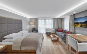- une chambre avec un grand lit et un canapé dans l'établissement Schwarzer Adler Kitzbühel - Adults Only, à Kitzbühel