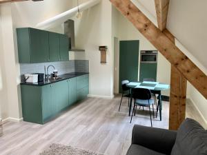 a kitchen with green cabinets and a table with chairs at B&B Vrijheid 4 in Arendonk