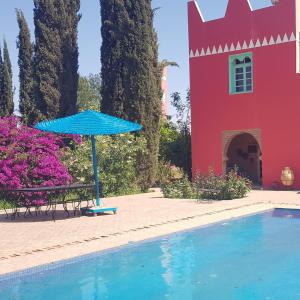 um guarda-chuva azul sentado ao lado de uma piscina em Riad-villa Le Jardin aux Etoiles em Sidi Boumoussa