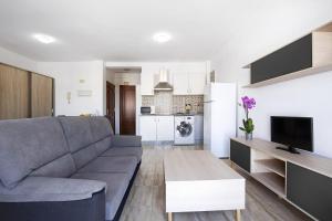 a living room with a gray couch and a kitchen at Apartamento Betty F in Puerto del Rosario