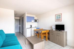 a living room with a blue couch and a kitchen at Residence Residhotel Mayflower in Le Grau-du-Roi