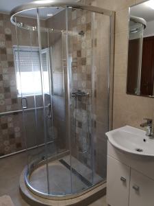 una ducha con una puerta de cristal junto a un lavabo en Kossuth Apartman en Hajdúszoboszló