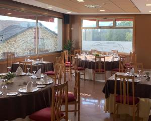 ein Restaurant mit Tischen und Stühlen und einem großen Fenster in der Unterkunft Hotel Bello in O Pino 