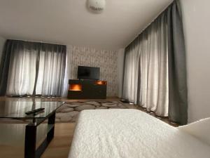 AMG Apartament في براشوف: غرفة نوم بسرير وطاولة وتلفزيون