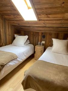 two beds in a room with wooden walls and ceilings at Le Tillau in Les Verrières-de-Joux +36 photos