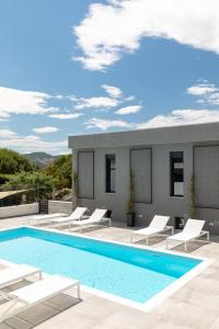 a swimming pool on the roof of a house with white chairs at Cove Suites in Iraklitsa