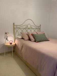a bed with pink pillows and a side table at Mirador de la ría, Isla Cristina in Isla Cristina