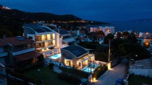 a large white house with lights on a city at night at Cove Suites in Iraklitsa