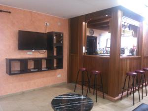 un bar con taburetes y TV en la pared en Hotel Chipiona, en Chipiona