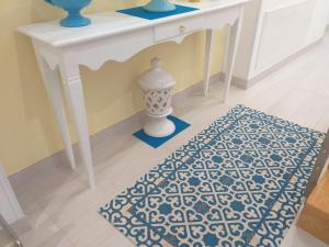 a white table with a blue and white rug on a floor at Falli Exclusive Rooms and Breakfast in Porto Cesareo