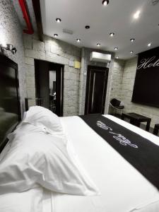 Hotel Plata by Bossh Hotels في بلدية إلبي: غرفة نوم بسرير ذو شراشف بيضاء وشاشة