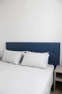 un lit avec une tête de lit bleue et des oreillers blancs dans l'établissement Villa San Martino - bilocale a Bussolengo, à Bussolengo