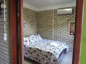 a small bedroom with a bed in a brick wall at Apê Namastê in Natal