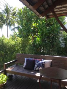 a wooden bench with pillows and a table on a deck at Jasmine & Tea House in Mae Nam