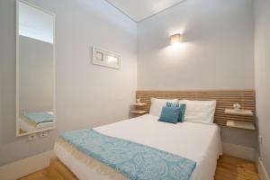 ein kleines Schlafzimmer mit einem Bett und einem Spiegel in der Unterkunft OPO Downtown Blue in Porto
