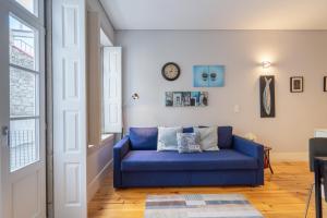 a blue couch in a living room with a clock on the wall at OPO Downtown Blue in Porto