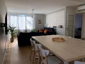 a kitchen and living room with a table and a couch at La Maison de la Douce Heure, 4 appartements climatisés avec jardin au centre ville proche des Thermes in Lons-le-Saunier