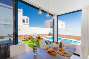 jadalnia ze stołem i widokiem na basen w obiekcie Villa Ariome w mieście Playa Blanca